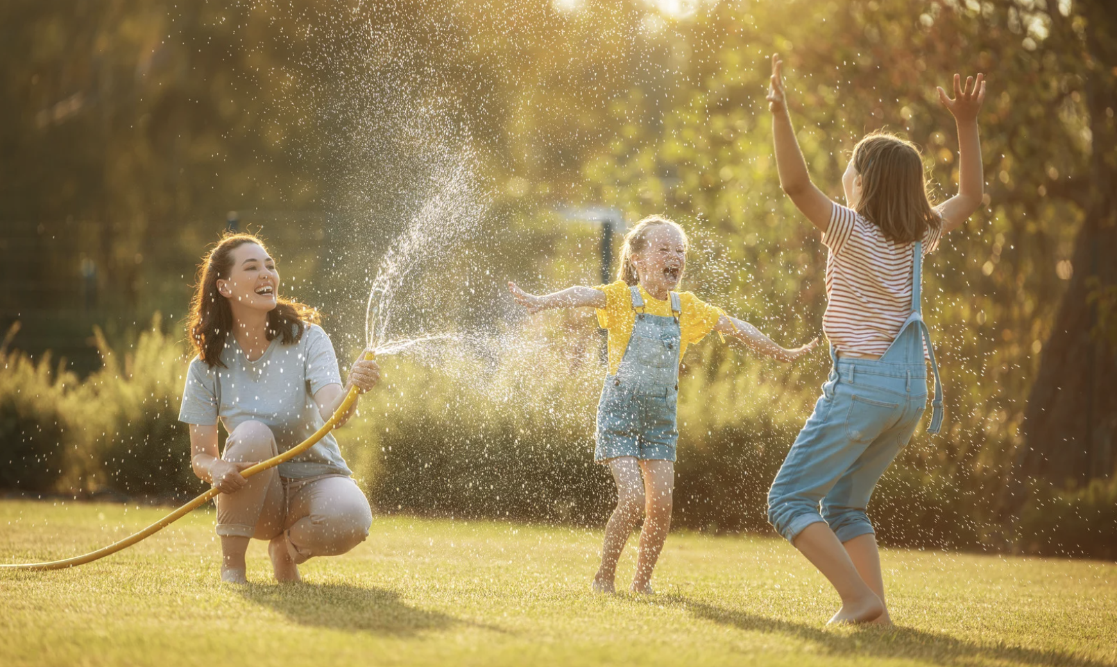 Family Playing in the Yard with a Sprinkler during summer housing market in New Mexico