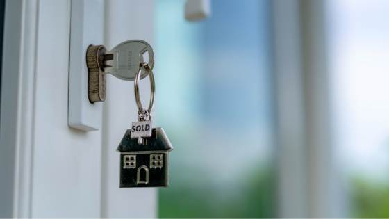 A door key with a house-shaped keychain hanging from it.