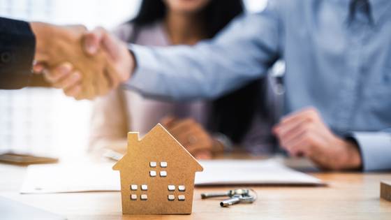 Two people shaking hands to finalize the sale of a home.