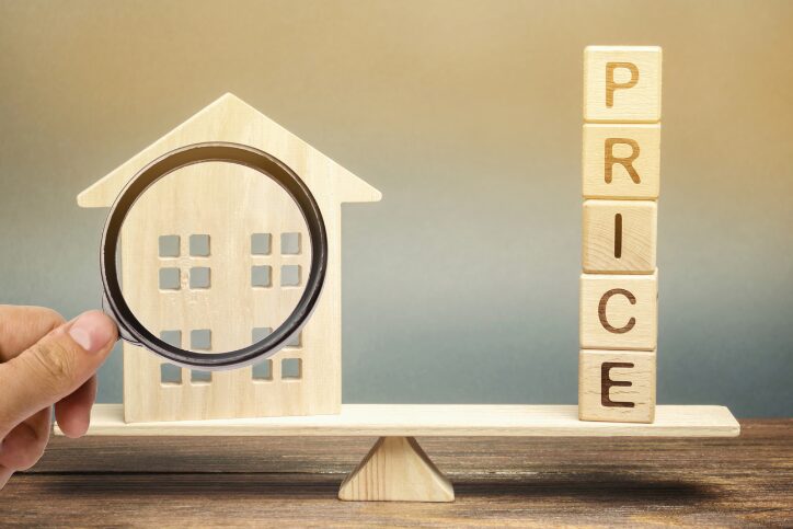 Scale with house models and price blocks representing home value